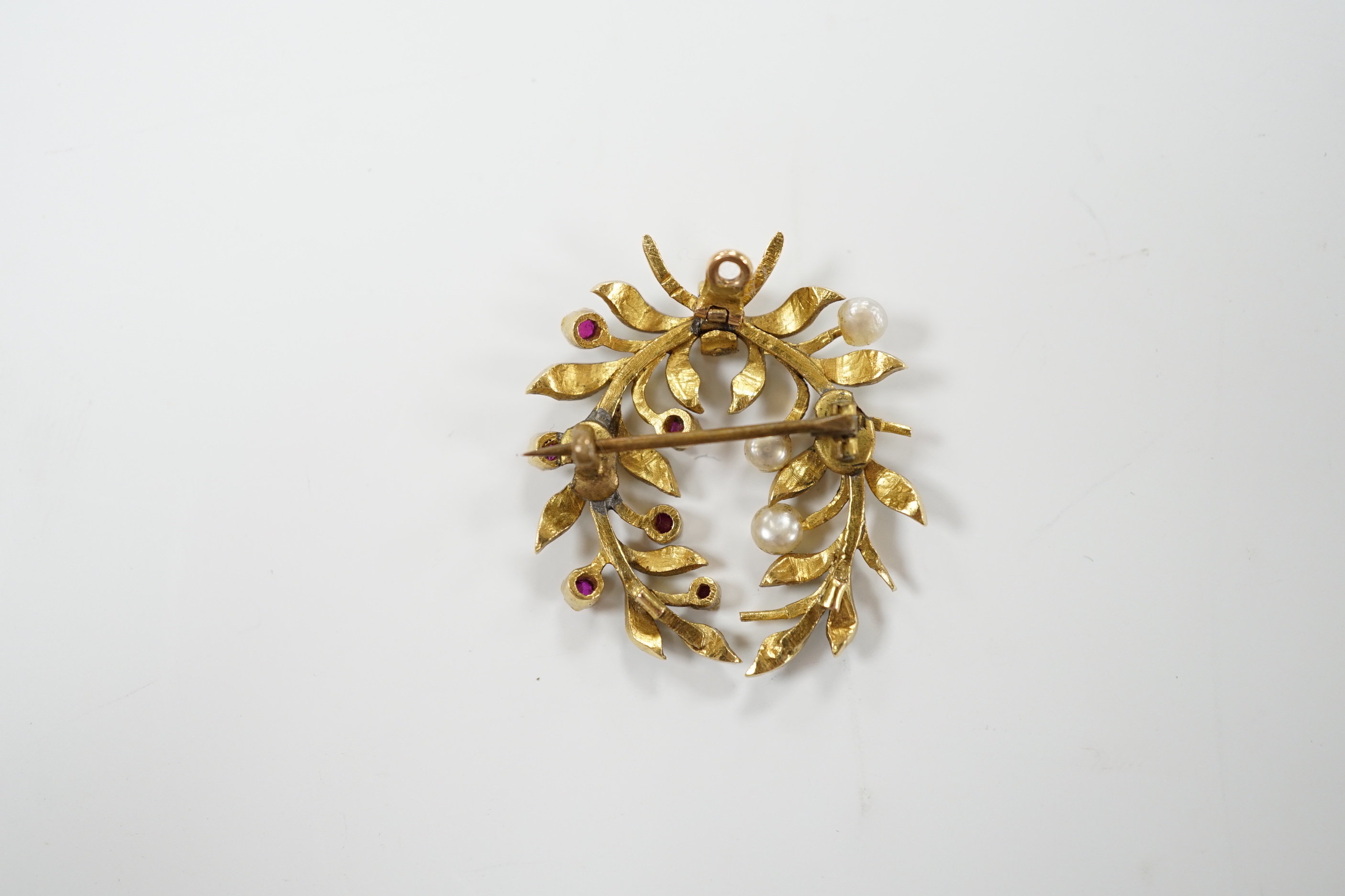 A yellow metal, green enamel, ruby and seed pearl cluster set wreath pendant brooch, 29mm, gross weight 6.9 grams.